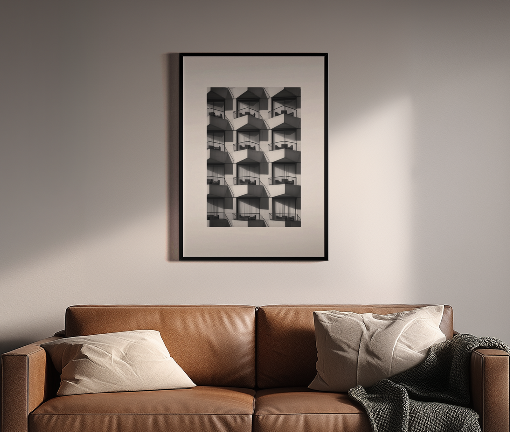 Repetitive Balkonfassade in Schwarz-Weiß Fotografie – Brutalismus Wandbild über braunem Ledersofa